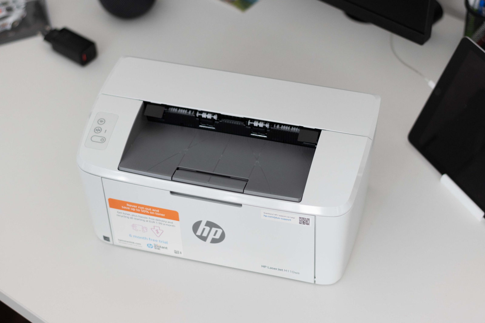 Tiskárna HP LaserJet M110we zeshora na kancelářském stole.