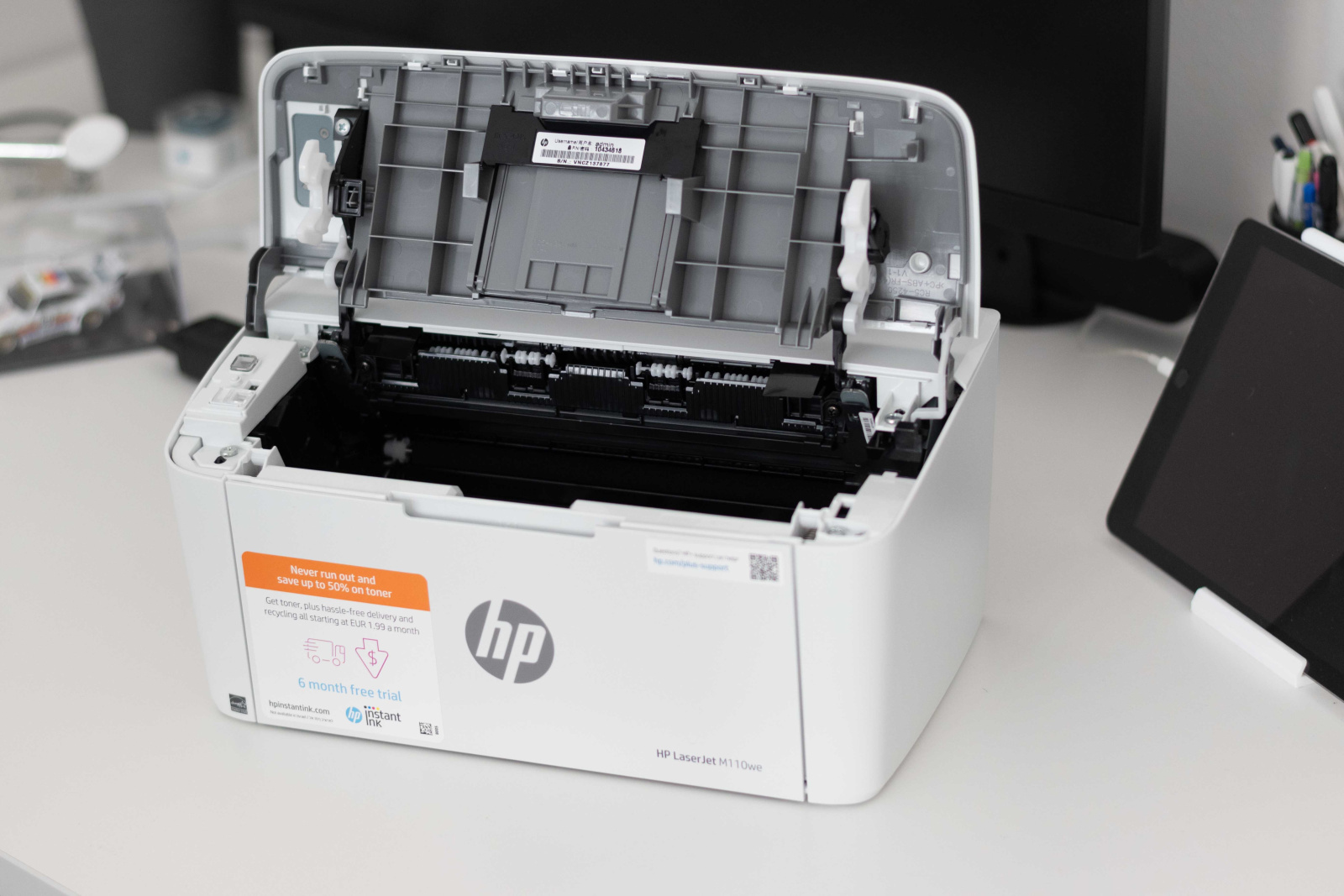 Tiskárna HP LaserJet M110we s odklopenou horní stranou pro vložení toneru. 
