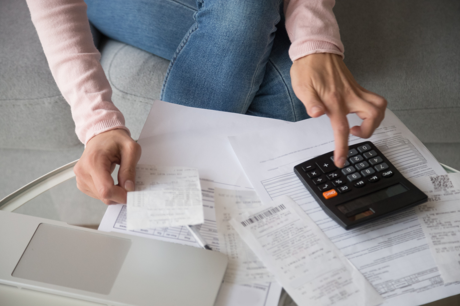 Žena držící v ruce účtenku při počítání na kalkulačce.